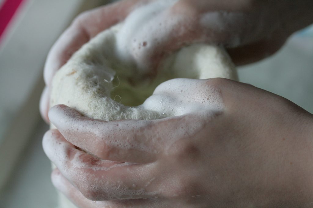 Die Wolle wird mit Seife und Handdruck auf ein Glas gefilzt.